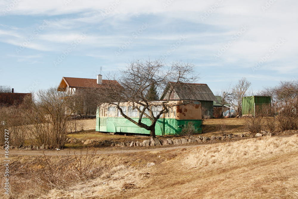Fototapeta premium Small countryside view with old bus in the middle in garden.