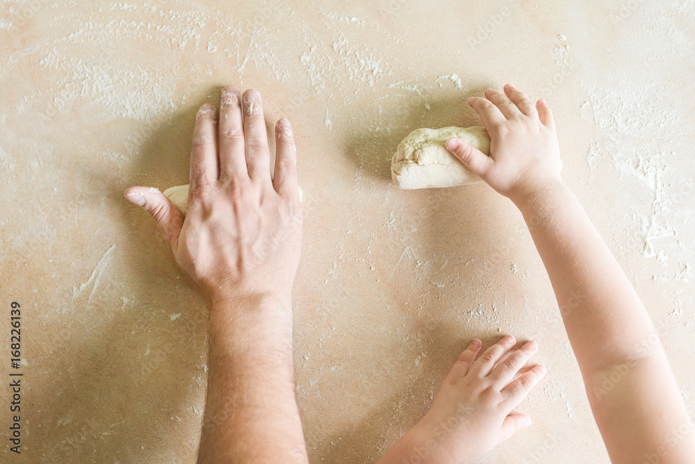 Fototapeta premium Children's and dad's hands makes raw dough
