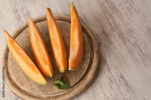 Slices of Cantaloupe on Wood Cutting Board Close Up photo