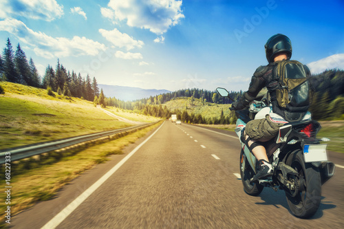 Fototapeta Naklejka Na Ścianę i Meble -  Motorcyclist rushes along the picturesque mountain highway