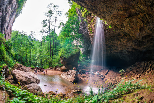 Beautiful scenic summer landscape of Chinarev waterfall in a gorge viewed from inside a rocky grotto in Caucasus mountains by Mezmai village, Russia