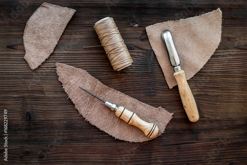 Tanner's workplace. Tools and matherials on dark wooden background top view photo