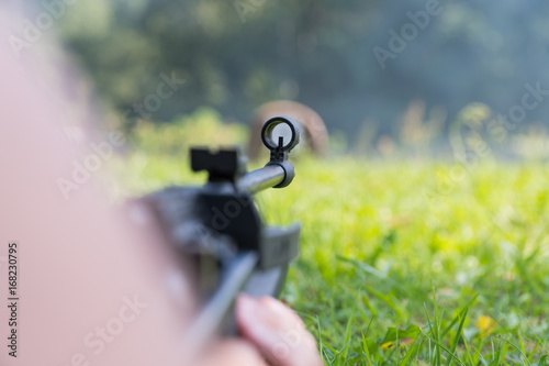 A man shoots a target from a pneumatic gun. A view from behind the shoulder