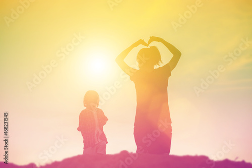 Mother encouraged her daughter out of the shadows at sunset.