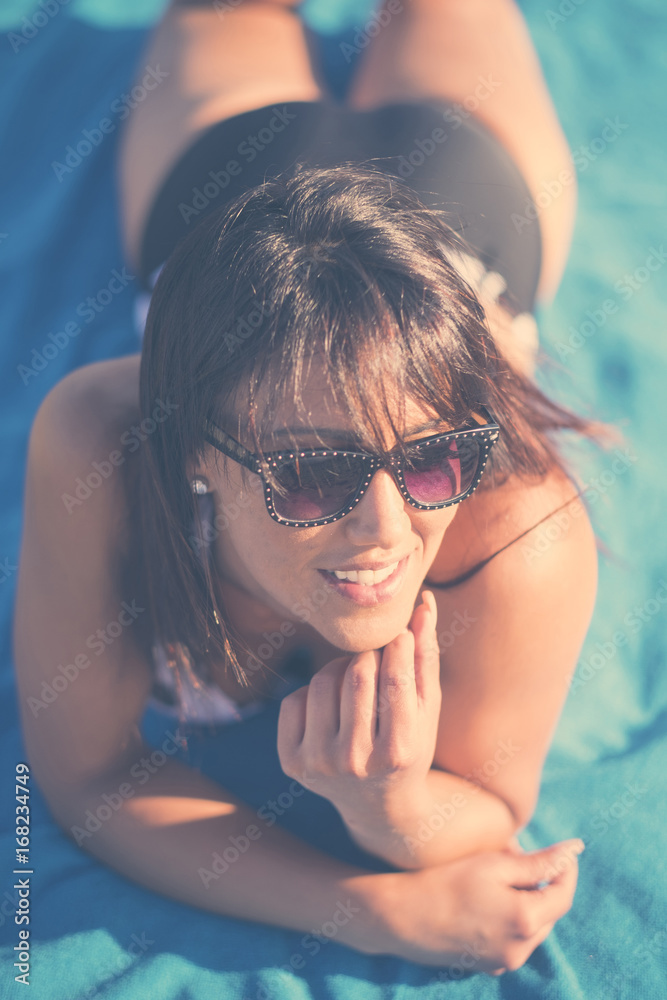 Caucasian woman laying on beach blanket Caucasian woman laying on beach blanket