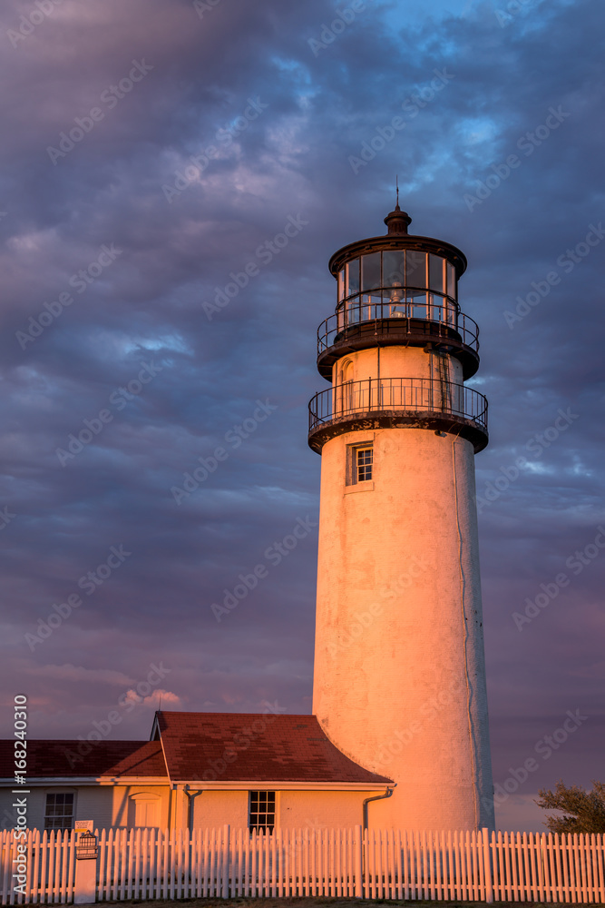 Lighthouse  at dusk with golden light against a dramatic sky of clouds 