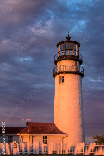 Lighthouse at dusk with golden light against a dramatic sky of clouds 