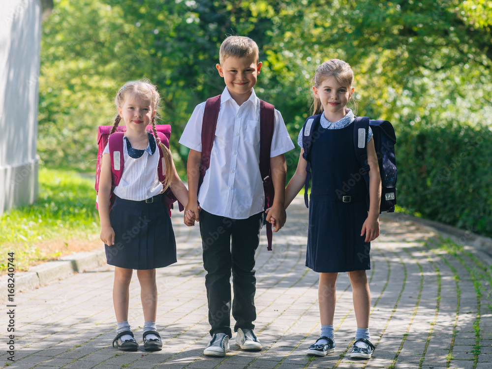 Happy school children in uniform with school bags, back to school