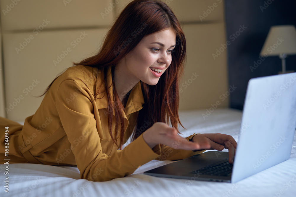 Young beautiful woman working behind laptop in bedroom on bed Young beautiful woman working behind laptop in bedroom on bed