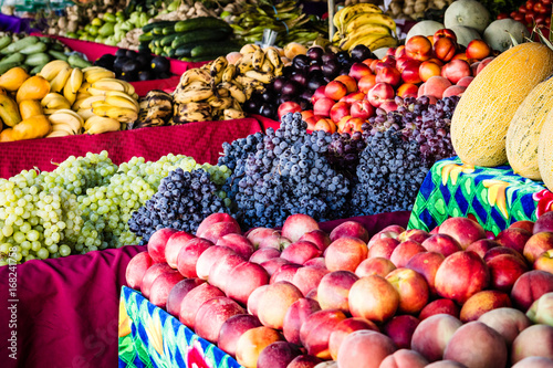 Farmers Market fruit stand with piles of colorful fresh picked fruits and vegetables, ready to be purchased and eaten.