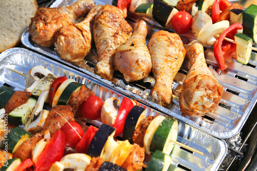 Skewers and chicken legs on barbecue