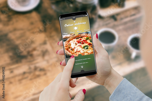 Girl ordering pizza with smartphone, while drinking coffee. Online order food concept