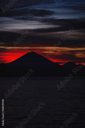 Bright tropical sunset and silhouettes of Agung volcano on the island of Bali in Indonesia.