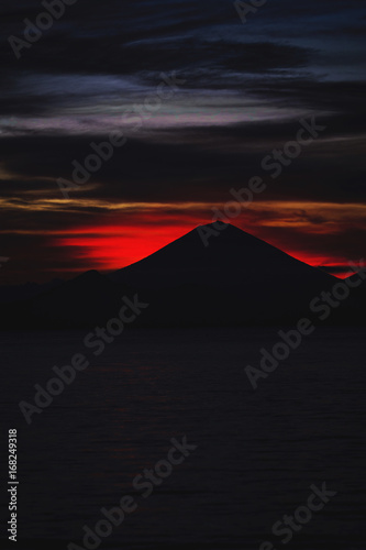 Bright tropical sunset and silhouettes of Agung volcano on the island of Bali in Indonesia.