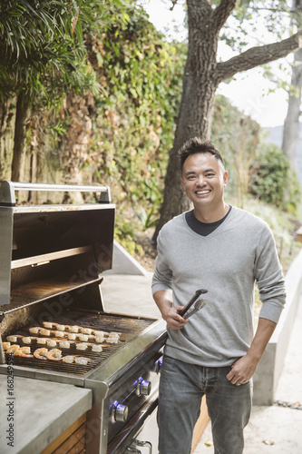 Portrait of smiling Chinese man cooking on grille photo