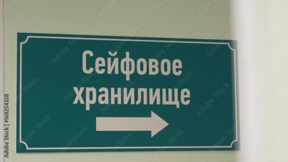 Green plastic sign on wall with arrow and white russian text sais safe depository, isolated close up Green plastic sign on wall with arrow and white russian text sais safe depository, isolated close up