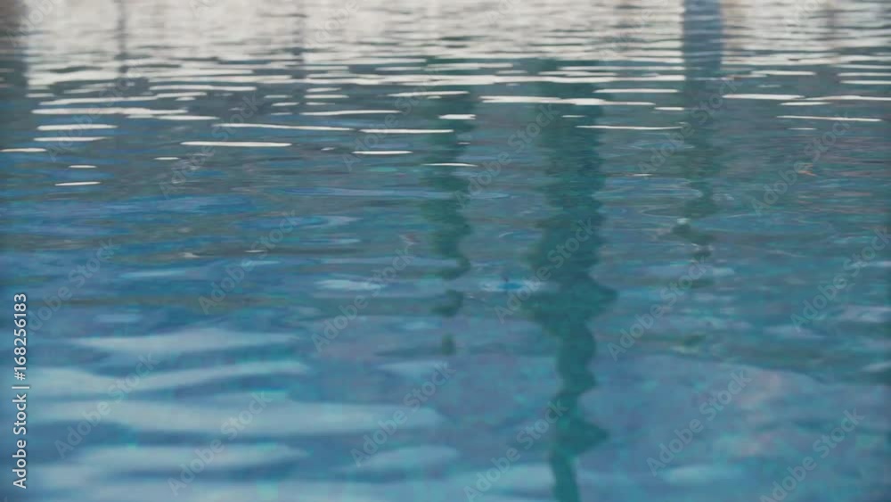 Isolated ripple water surface of swimming pool with blue tiled bottom on summer sunny day Isolated ripple water surface of swimming pool with blue tiled bottom on summer sunny day