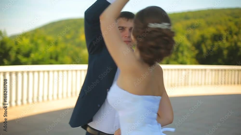 The bride and groom dance a wedding dance on a beautiful balcony overlooking the sea The bride and groom dance a wedding dance on a beautiful balcony overlooking the sea