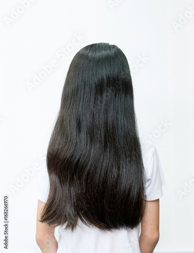 Portrait of beautiful young Asian teenage girl with long wavy black hair. Back view of children with dry hair on white background. Hair Damage, Health And Beauty Concept.