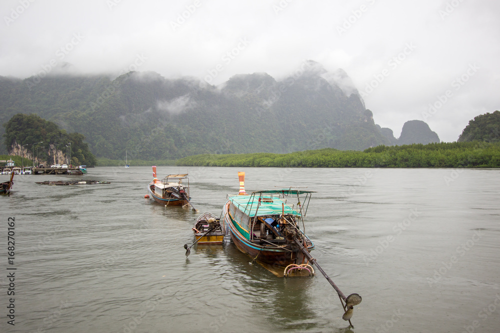 Long-tailed boats and overcast sky at Ao Thalane(Thalane Bay),Khao Thong,Krabi Province,southern Thailand.