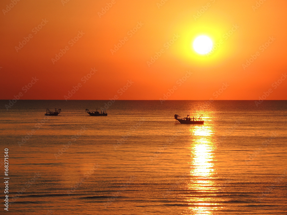 Fishing boats pull their nets at the sunrise. Adriatic cost. Emilia Romagna. Italy
