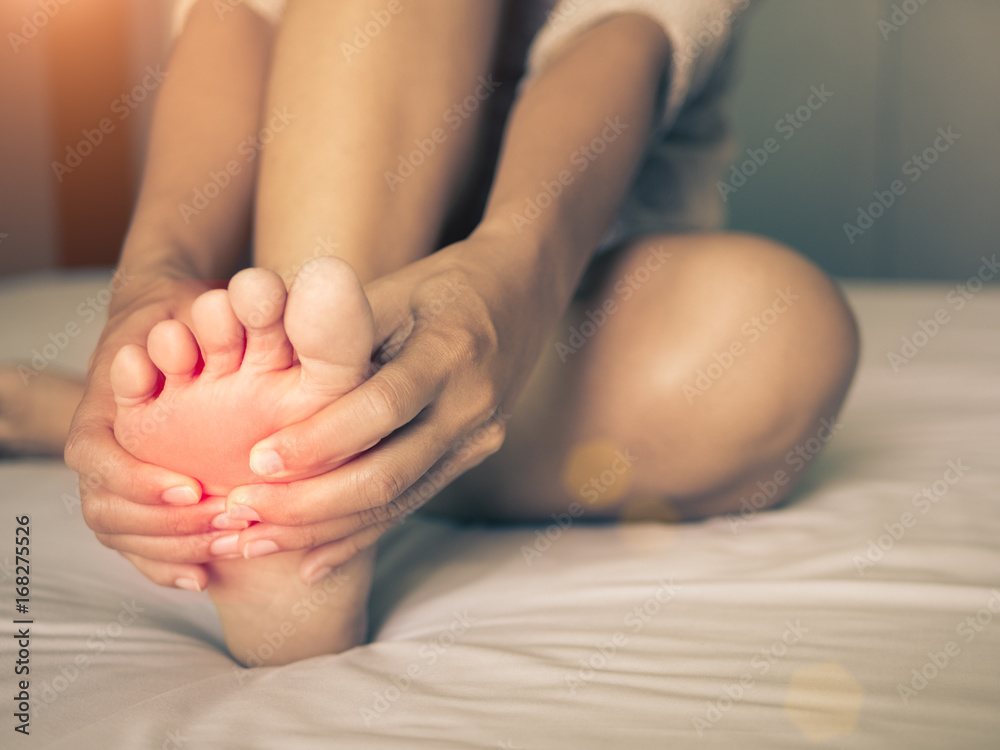 health care concept. woman massaging her painful foot, red hi-lighted on pain area health care concept. woman massaging her painful foot, red hi-lighted on pain area