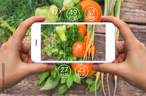 Smartphone in hand with information of calories in vegetables. photo