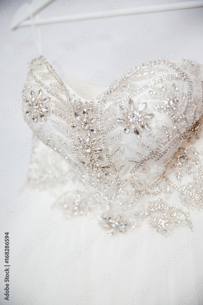 Close-up white wedding dress embroidered with rhinestones, beads, glitter.  Corset. Concept engagement, clothes for the bride. Stock Photo