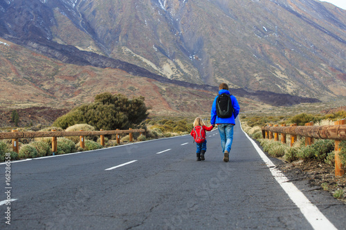father with little daughter walking on road, family travel