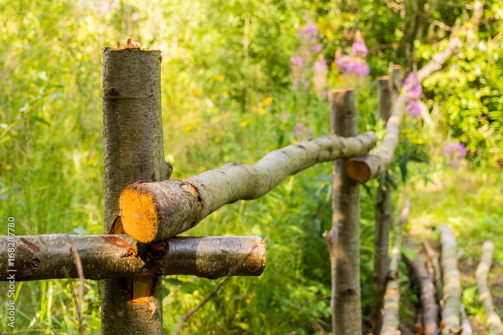 The fence is handmade from trees trunk. The rural design of the fence site. Fence for the cattle in the village. The fence is handmade from trees trunk. The rural design of the fence site. Fence for the cattle in the village.