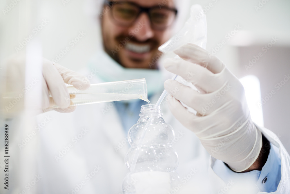 Young scientist is mixing reagents in a glass flask in a clinical laboratory. Young scientist is mixing reagents in a glass flask in a clinical laboratory.
