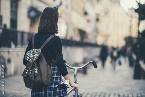 Hipster girl with a bike walking on the street