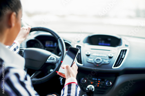 Rear view of businesswoman holding mobile while driving a car.