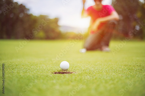 golf ball on green golf course, sunrise morning light. 