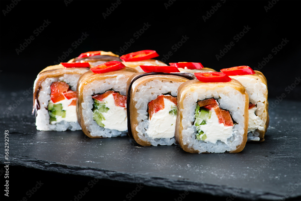 Traditional Japanese cuisine. Selective focus on set of sushi rolls with salmon, cream cheese, rice, chili pepper and cucumber on dark background Traditional Japanese cuisine. Selective focus on set of sushi rolls with salmon, cream cheese, rice, chili pepper and cucumber on dark background