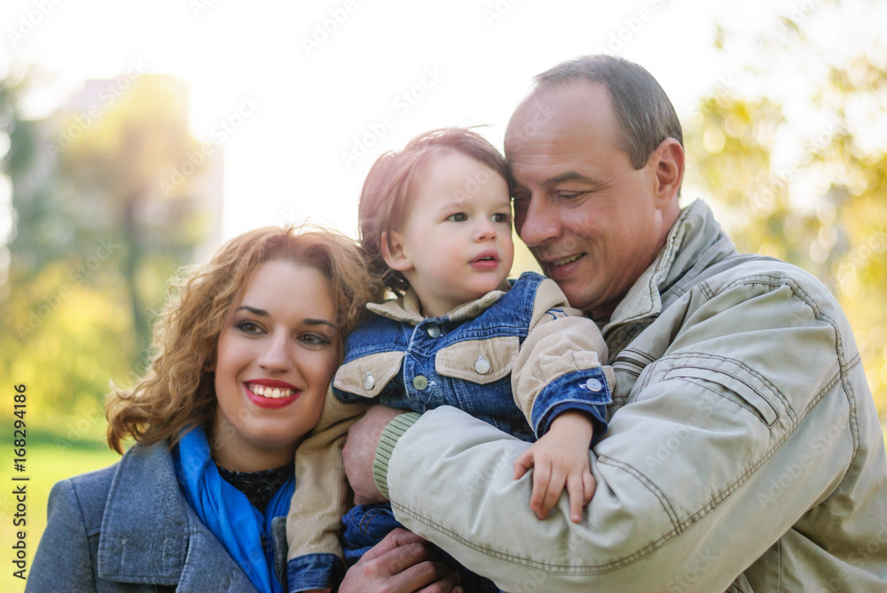 Fototapeta premium Young family, mom, dad and son hugging and show mutual love