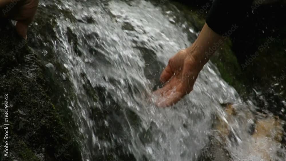 Man touches water in a mountain stream Man touches water in a mountain stream