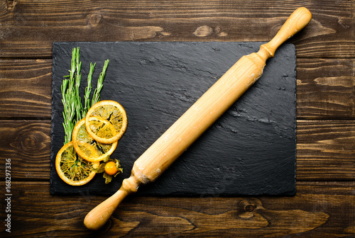 sliced lemon, herbs and pestle on wooden background, top view