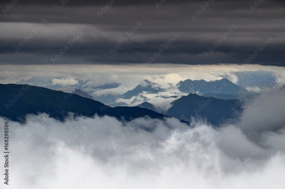 Low hanging cloud layers swirl around and above the ridges of Carnic Alps and Julian Alps in the background, Friuli Venezia Giulia region, Northern Italy, Europe Low hanging cloud layers swirl around and above the ridges of Carnic Alps and Julian Alps in the background, Friuli Venezia Giulia region, Northern Italy, Europe