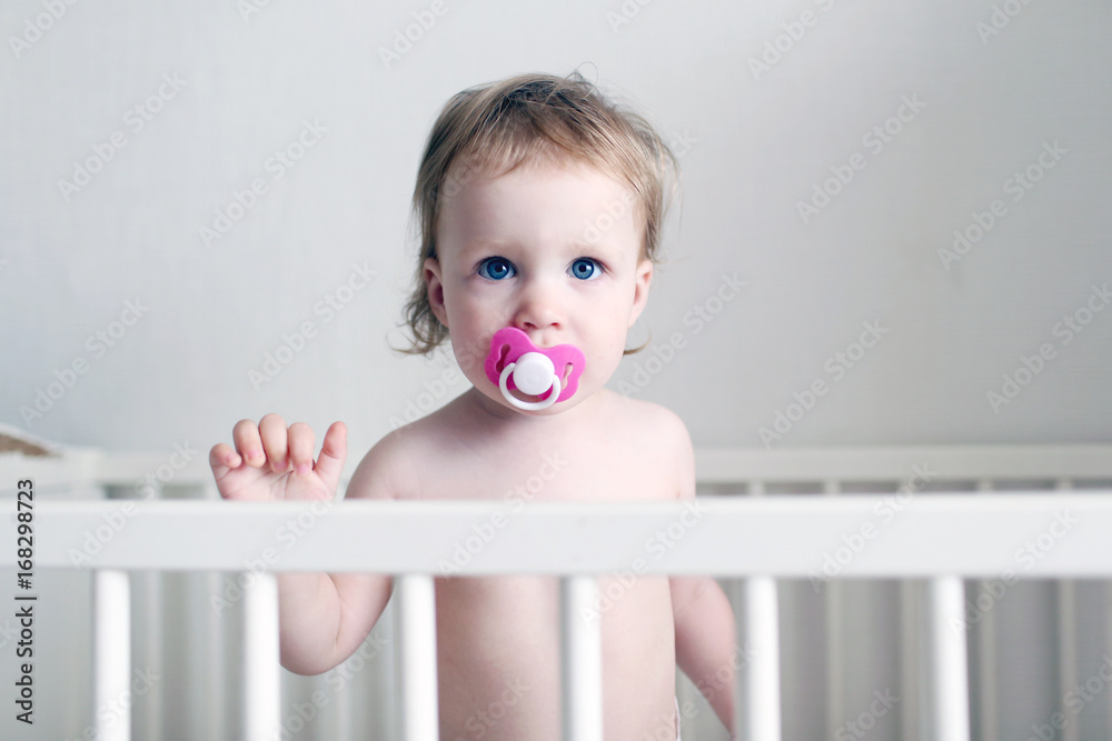 Little 1 years baby girl with dummy in white bed Little 1 years baby girl with dummy in white bed