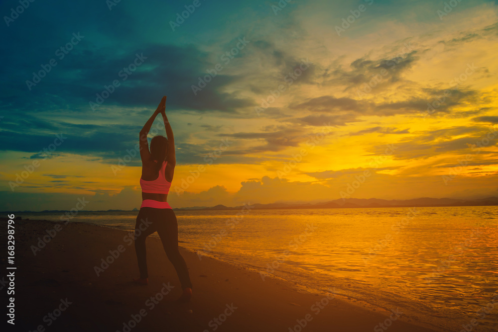 Silhouette young woman practicing yoga on the beach at sunset. Vintage tone