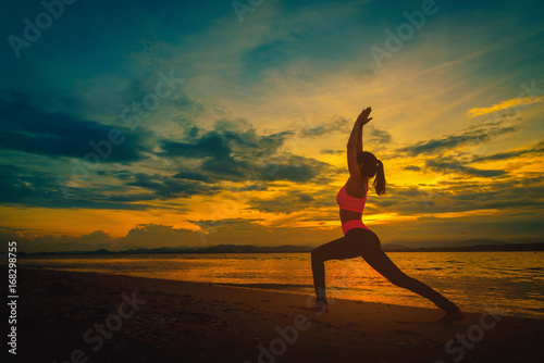 Silhouette young woman practicing yoga on the beach at sunset. Vintage tone