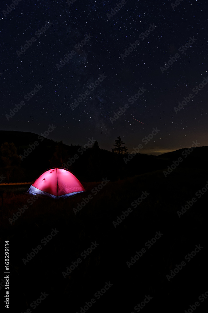 Night under the tent. People inside tent. Sky full of the stars. View on milky way.