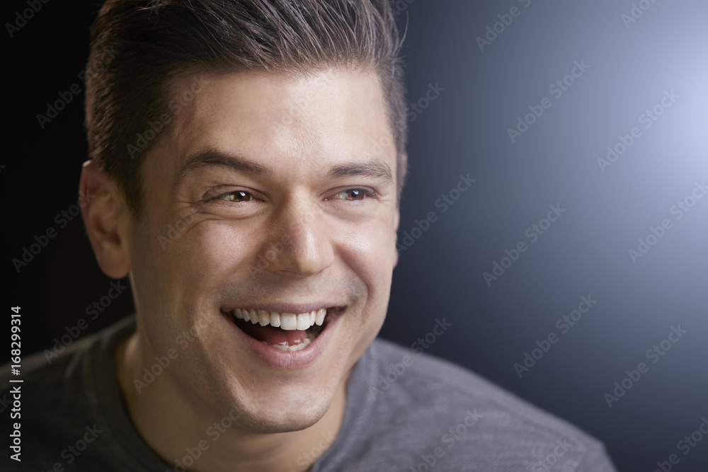 Fototapeta premium Portrait of a smiling young white man on black background