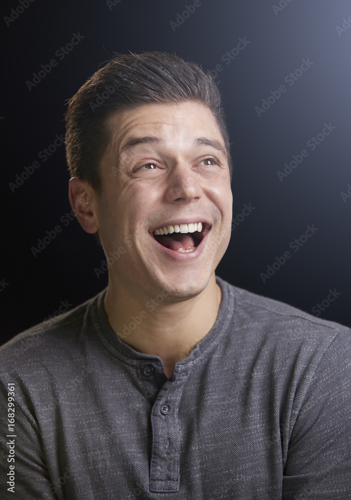 Laughing young man looking up, vertical portrait Laughing young man looking up, vertical portrait