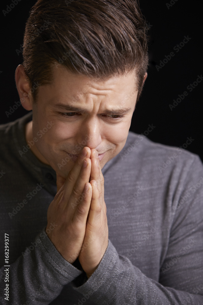 Worried young man with hands clasped, vertical portrait Worried young man with hands clasped, vertical portrait