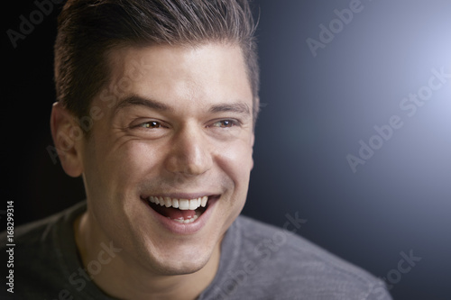 Portrait of a smiling young white man on black background