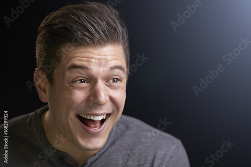 Portrait of a laughing young white man on black background