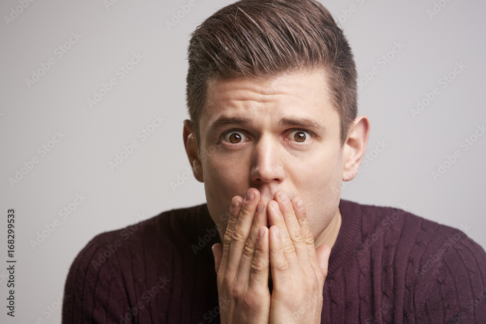 Close up portrait of a scared young man with hands to face Close up portrait of a scared young man with hands to face