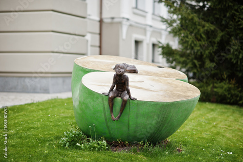 Sculpture of a boy sitting on something in the park. photo